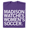 A folded purple t-shirt with left aligned text in white ink that reads "Madison watches women's soccer"