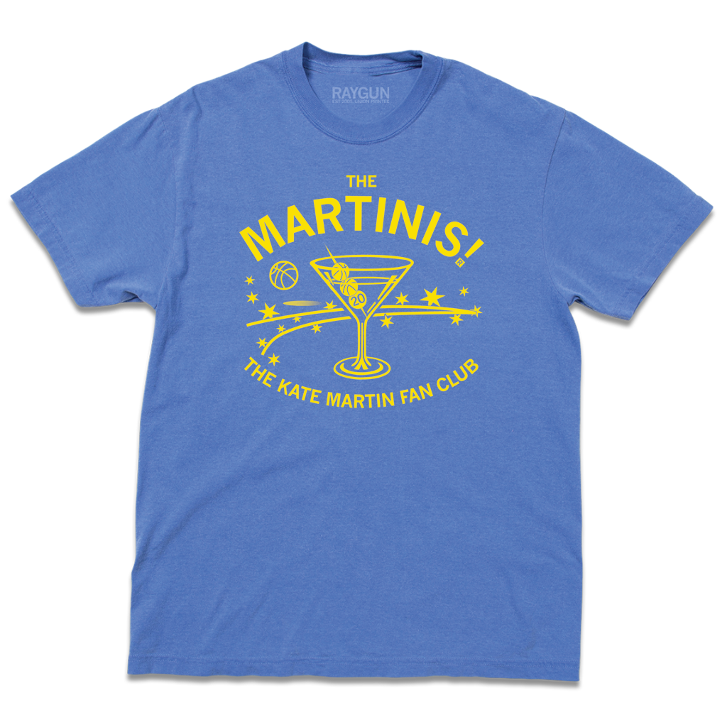 Comfort Colors flo blue heavyweight t-shirt with bright yellow ink. The center is an illustration of a martini glass with tiny basketballs on a toothpick in place of olives. Curved text above says "The MARTINIS!" and smaller fond below the image adds "THE KATE MARTIN FAN CLUB." There's also a bouncing basketballs, scatters stars, and other accents.