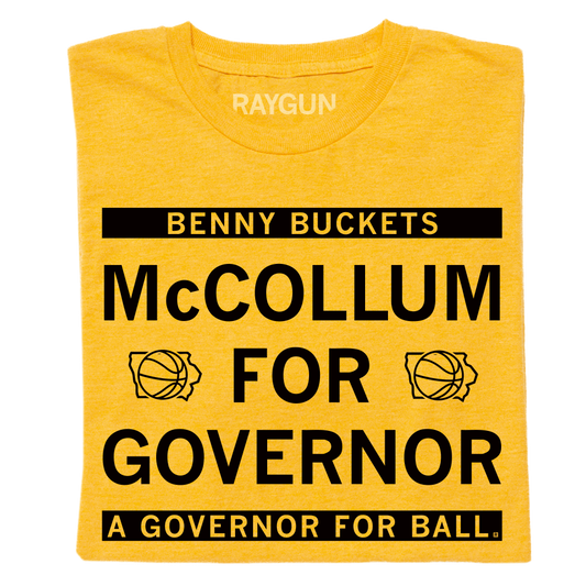 A folded heather gold shirt with black ink text that reads "Benny Buckets. McCollum for Governor. A Governor for ball."