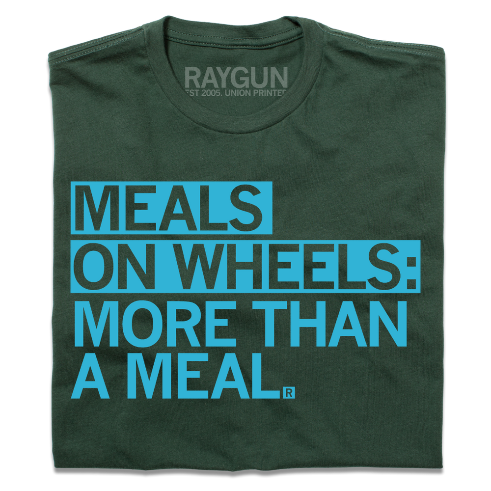 A folded forest green t-shirt with left-aligned bright blue text that reads "Meals On Wheels: More than a meal" in all caps.