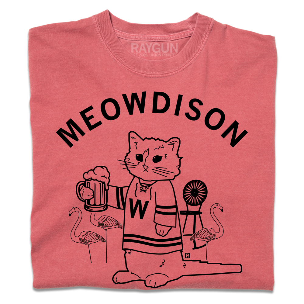 A folded heavyweight red t-shirt with black ink. Curved text at the top says, "Meowdison" above an illustration of a cat holding a pint of beer while wearing a hockey jersey. There are lawn flamingos and a rocking chair in the background.