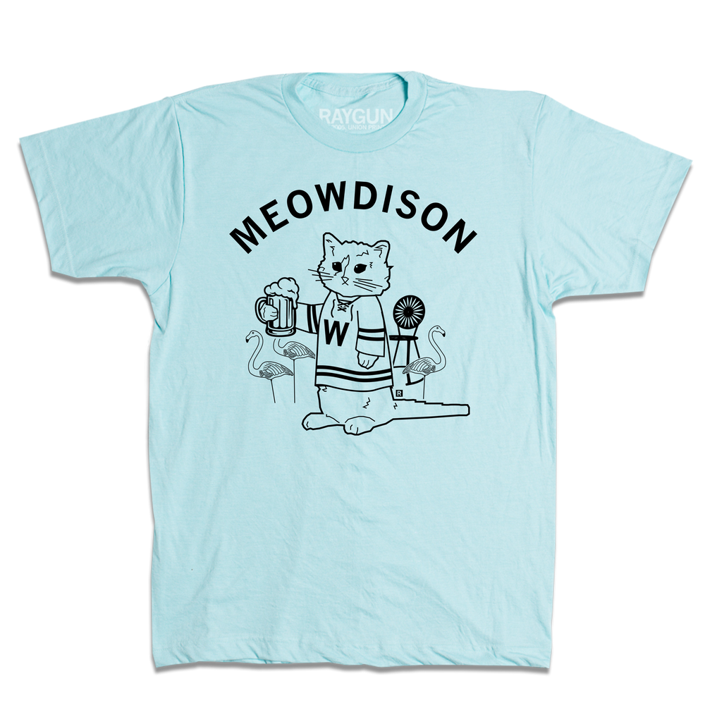 Short-sleeve heather pastel blue t-shirt with black ink. Curved text at the top says, "Meowdison" above an illustration of a cat holding a pint of beer while wearing a hockey jersey. There are lawn flamingos and a rocking chair in the background.