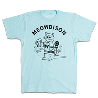 Short-sleeve heather pastel blue t-shirt with black ink. Curved text at the top says, "Meowdison" above an illustration of a cat holding a pint of beer while wearing a hockey jersey. There are lawn flamingos and a rocking chair in the background.