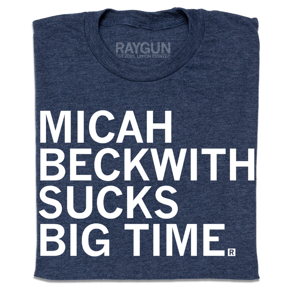 A folded heather navy t-shirt with left-aligned white print text that reads "Micah Beckwith sucks big time" in all caps.