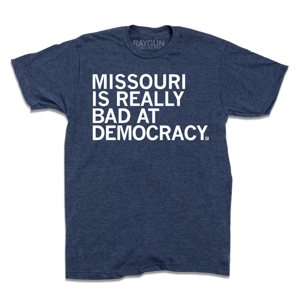 Short-sleeve heather denim t-shirt with white text that says, "MISSOURI IS REALLY BAD AT DEMOCRACY."