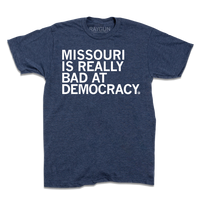 Short-sleeve heather denim t-shirt with white text that says, "MISSOURI IS REALLY BAD AT DEMOCRACY."
