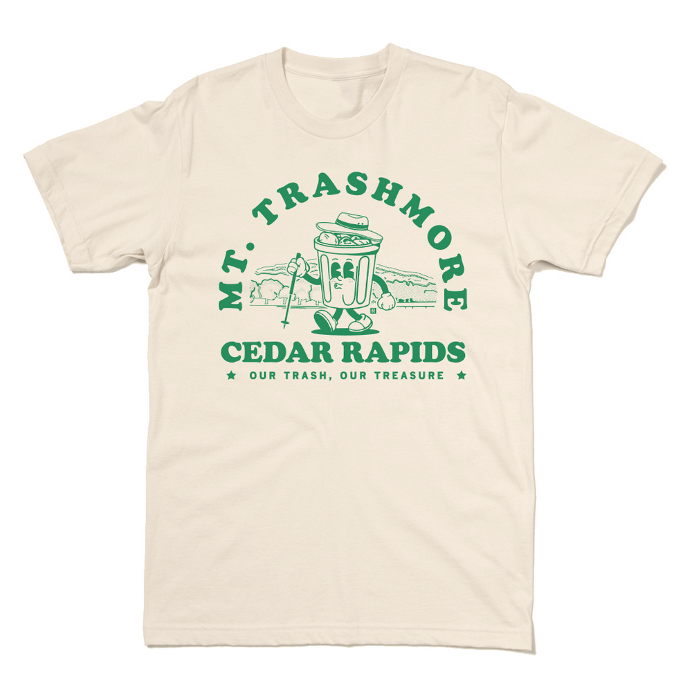 Natural colored t-shirt with green ink that reads "Mt. Trashmore, Cedar Rapids. Our trash, our treasure" framing an image of a cartoon trashcan going for a hike with Mt. Trashmore in the background.