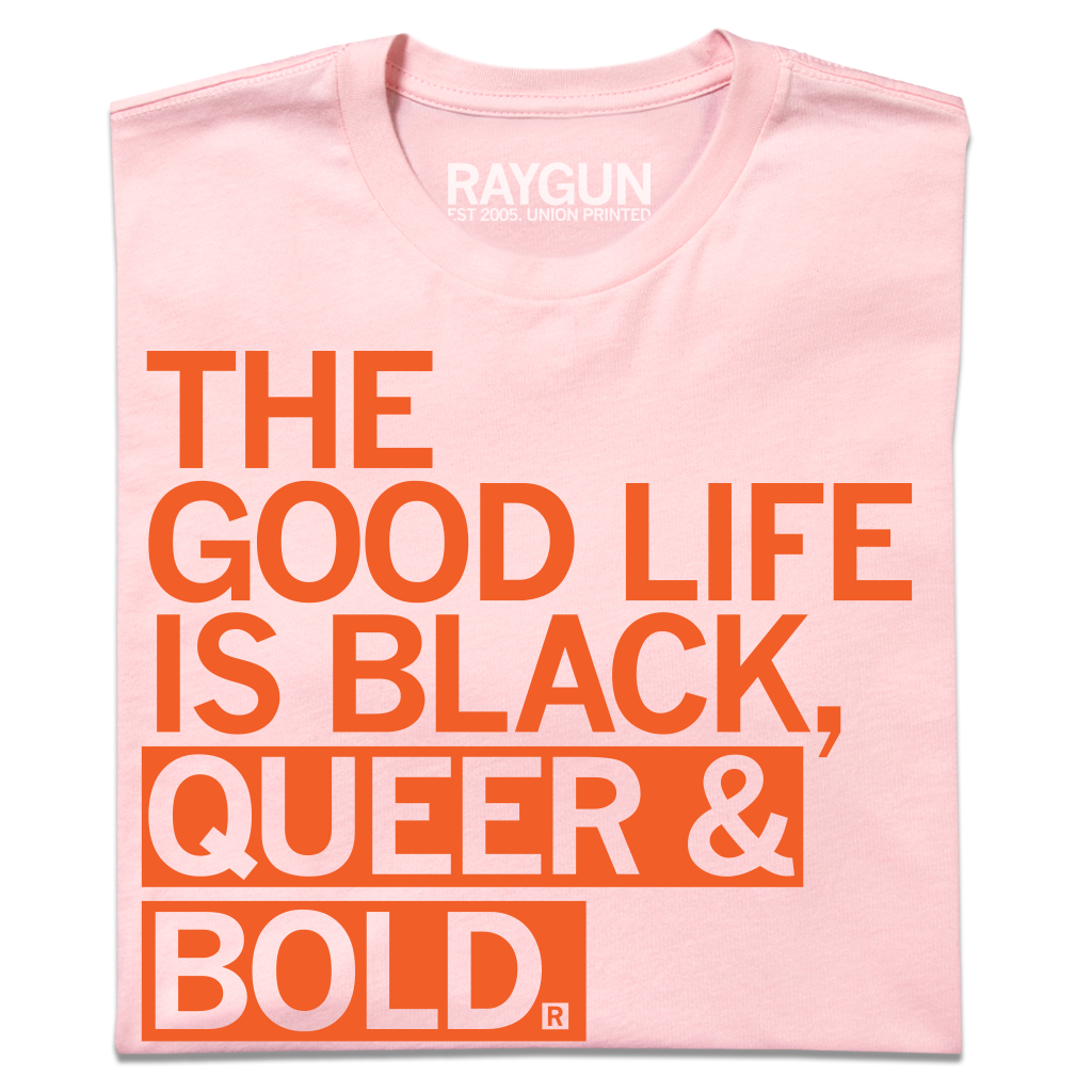 A light pink Black Pride t-shirt with orange text that reads, THE GOOD LIFE IS BLACK, QUEER & BOLD.