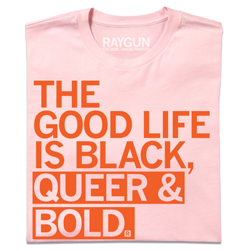 A light pink Black Pride t-shirt with orange text that reads, THE GOOD LIFE IS BLACK, QUEER & BOLD.