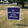 A 12x12 inch RAYGUN yard sign on a lawn reads, NO DATA CENTERS IN THE DRIFTLESS.