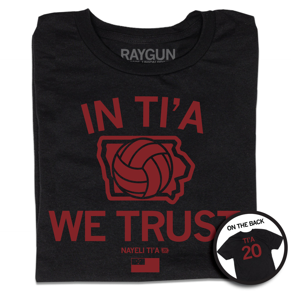 Folded black t-shirt with red ink print depicting Iowa in the center with a volleyball taking up most of the state. Text above and below Iowa says, "IN TI'A WE TRUST" with "NAYELI TI'A" in smaller  print below. Beside her name is a tiny Iowa with the number 20 in it and at the bottom of the print is the flag for Samoa. A circular image in the bottom right shows the back print. The back is laid out like a jersey with "TI'A" printed above 20.