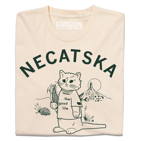 A folded cream t-shirt with dark green ink. Curved text across the top says, 