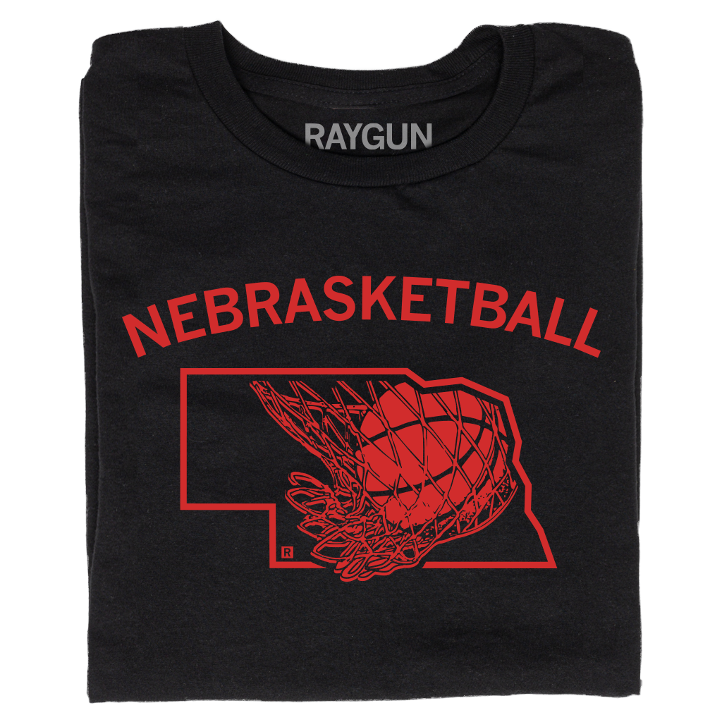A folded black t-shirt with brite red ink and curved text that says, "Nebrasketball" above an outline of Nebraska with a basketball going through a hoop.