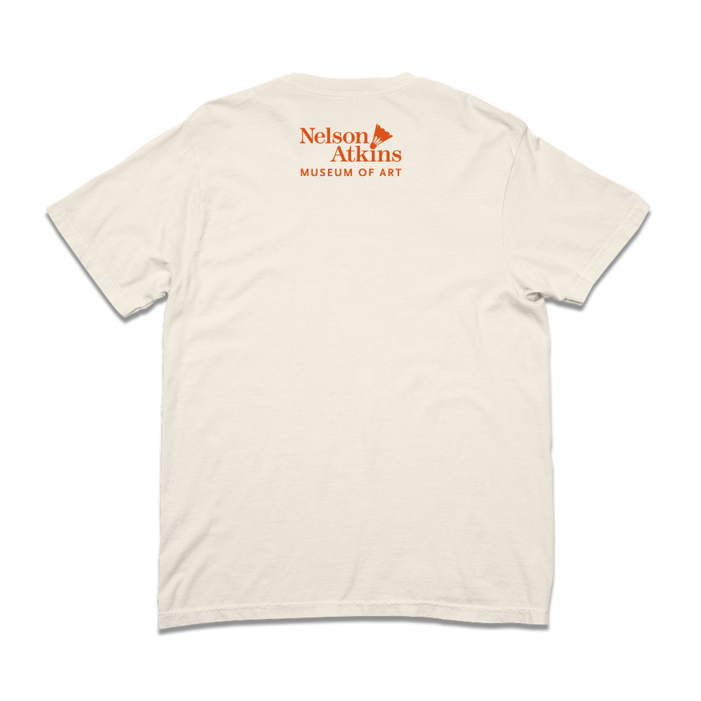 The back of a comfort colors ivory shirt with orange text that says, "Nelson Atkins Museum of Art." The front features a giant badminton shuttlecock.