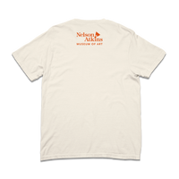 The back of a comfort colors ivory shirt with orange text that says, "Nelson Atkins Museum of Art." The front features a giant badminton shuttlecock.