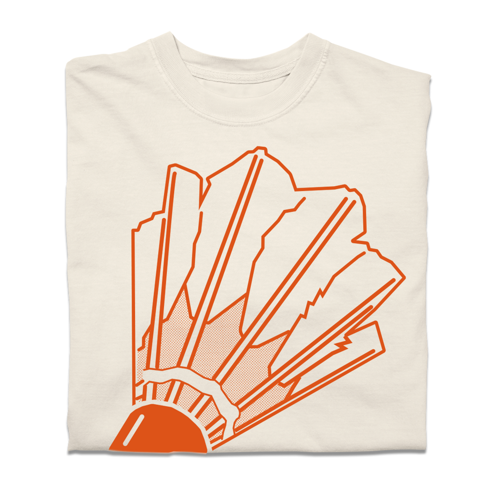 A folded comfort colors ivory t-shirt with orange ink depicting a giant badminton shuttlecock on the front and the text "Nelson Atkins Museum of Art" on the back.