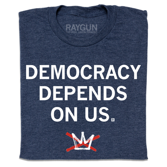 A folded heather navy t-shirt with centered white ink text that reads "Democracy Depends On Us" above the No Kings logo.