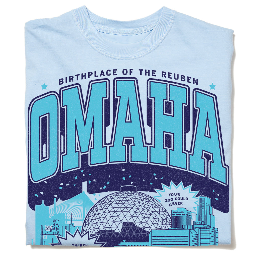 Light blue garment-dyed heavyweight cotton t-shirt with a graphic that reads Birthplace of the Reuben and Omaha, featuring city skyline illustrations and a speech bubble that says Your zoo could never.