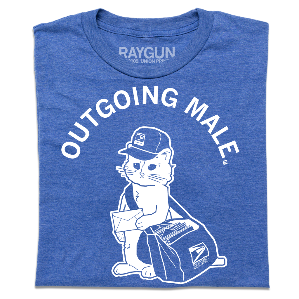 A folded heather blue short sleeve t-shirt with curved white text near the top that says, "OUTGOING MALE" above an illustration of a cat dressed as a mail carrier with a mail back over his shoulder and a letter in hand.