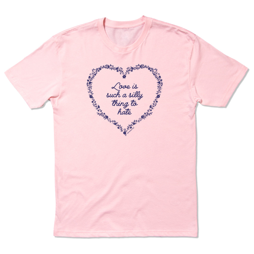 A light pink, combed ringspun cotton RAYGUN t-shirt featuring a purple floral heart design enclosing the text, Love is such a silly thing to hate.
