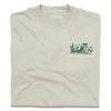 Light beige, garment-dyed heavyweight t-shirt with a chest pocket featuring a green line-art print of wildflowers and a butterfly.