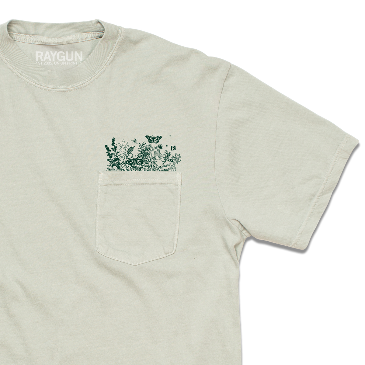 Light gray garment-dyed t-shirt with a chest pocket featuring a dark green botanical print of leaves, flowers, and a butterfly.