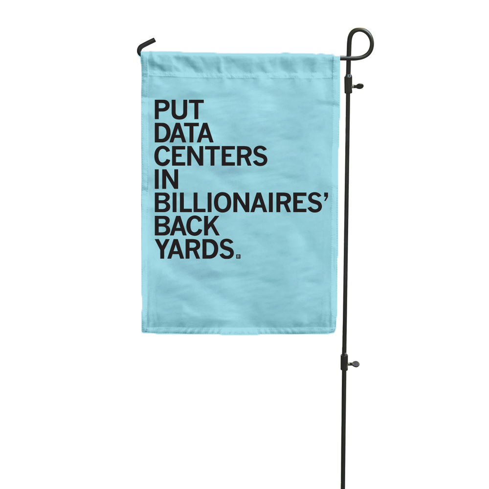 A light blue garden flag hanging vertically from a flag pole with black text that reads "Put data centers in billionaires' back yards."