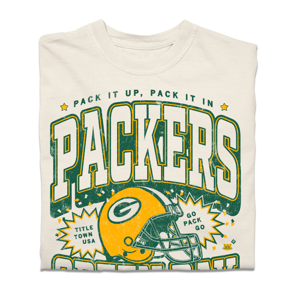 A folded heavyweight ivory t-shirt with yellow and gold print that reads "Pack it up, pack it in. Title Town USA. Go Pack go. Green Bay Packers est. 1919. Lambeau Field." A  Green Bay Packers helmet is in the center and the design is laid out like a vintage college shirt.