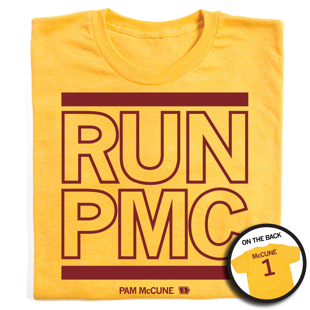 Folded heather yellow t-shirt with cardinal ink print that says, "RUN PMC" in large, outlined text with a thick red line printed above and below. Smaller print at the bottom reads "PAM McCune" beside a tiny Iowa with the number 1 in it. The back of the shirt is printed like a jersey with "McCune" across the shoulders above a large number 1.