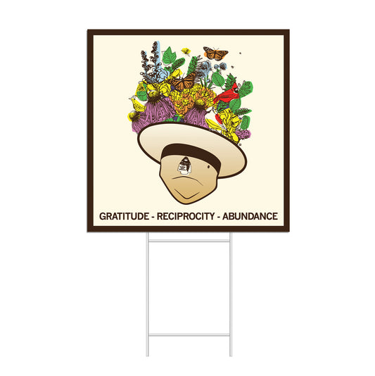A RAYGUN yard sign featuring a person wearing a wide-brimmed hat topped with flowers, birds, and butterflies, with the text GRATITUDE - RECIPROCITY - ABUNDANCE printed at the bottom.