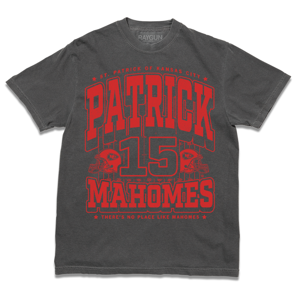 Dark grey shirt with bright red ink that reads "Saint Patrick of Kansas City. Patrick Mahomes #15. There's No Place Like Mahomes" over an illustration of a football field with a football helmet to either side.