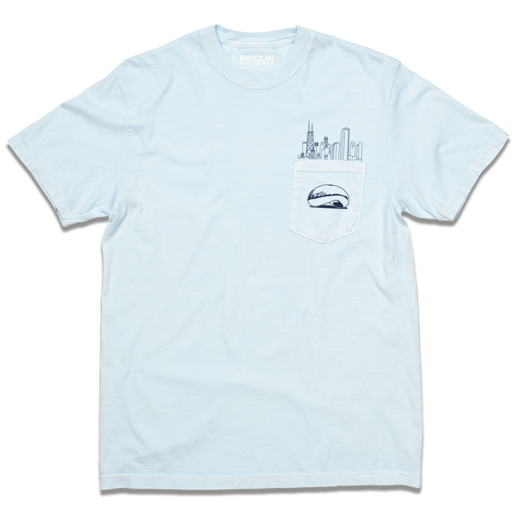 A light blue pocket t-shirt with navy ink. An illustration of the Chicago skyline is printed above the pocket with the Cloud Gate statue printed on the pocket.