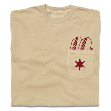 A folded beige pocket tee with dark red print of two hotdogs above the pocket and a Chicago flag star on the pocket.