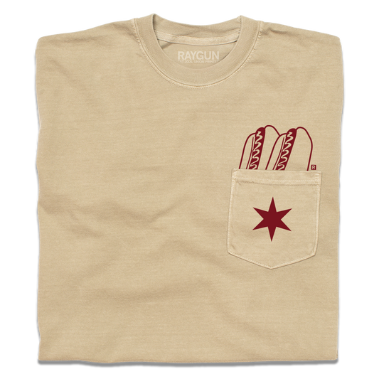 A folded beige pocket tee with dark red print of two hotdogs above the pocket and a Chicago flag star on the pocket.