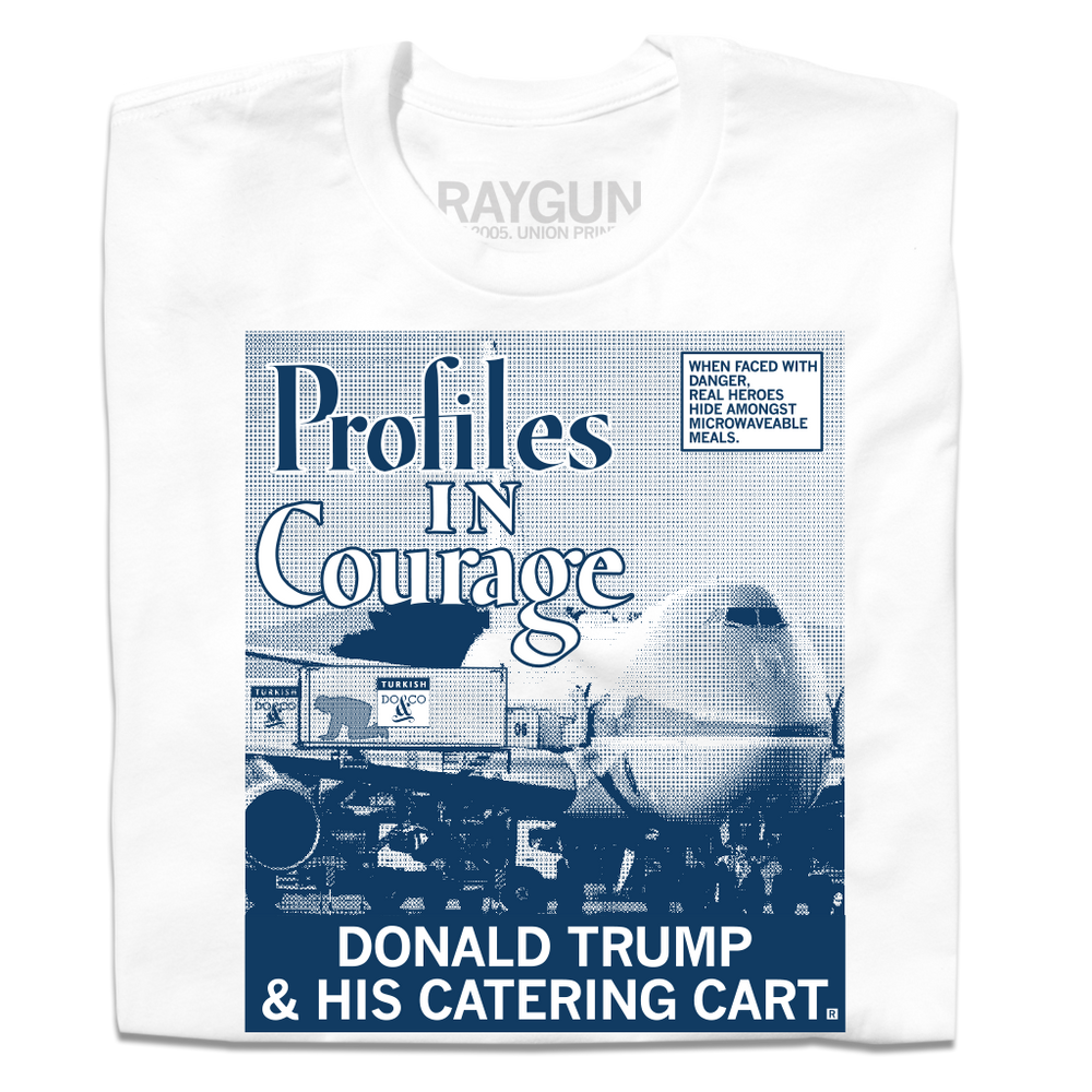 Folded white shirt with a picture printed as a gradient with navy ink. The image is of a plane landed at an airport loading Donald Trump hiding in a food cart into the plane. A white square with a blue outline and blue text in the top right reads "WHEN FACED WITH DANGER, REAL HEROES HIDE AMONGST MICROWAVEABLE MEALS." Large text in the top left says, "Profiles In Courage" and smaller white font at the bottom of the print reads "DONALD TRUMP & HIS CATERING CART."