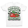 A white tee with text in black, green, and white that reads "Just another proud public educator. Teach, change lives, repeat" around a red apply with a bookworm popping out and a stack of red & green books in the back.