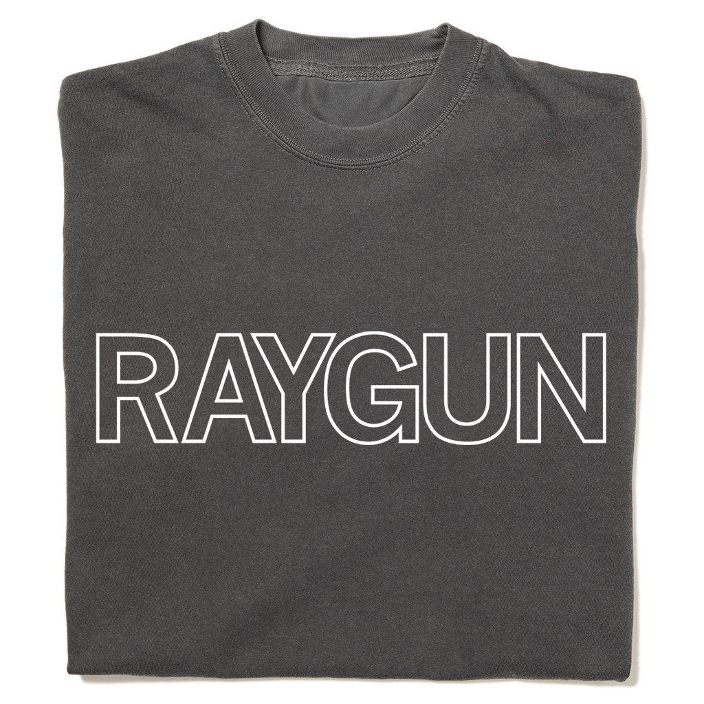 A folded heavyweight grey t-shirt with white outlined text that says, "RAYGUN" across the chest.