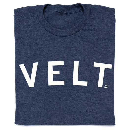 A folded, union-made navy blue t-shirt with the word VELT printed in large white capital letters.