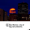 Illuminated red neon sign of an umbrella above the text THE TRAVELERS atop a building at night, iconic as a Des Moines landmark.