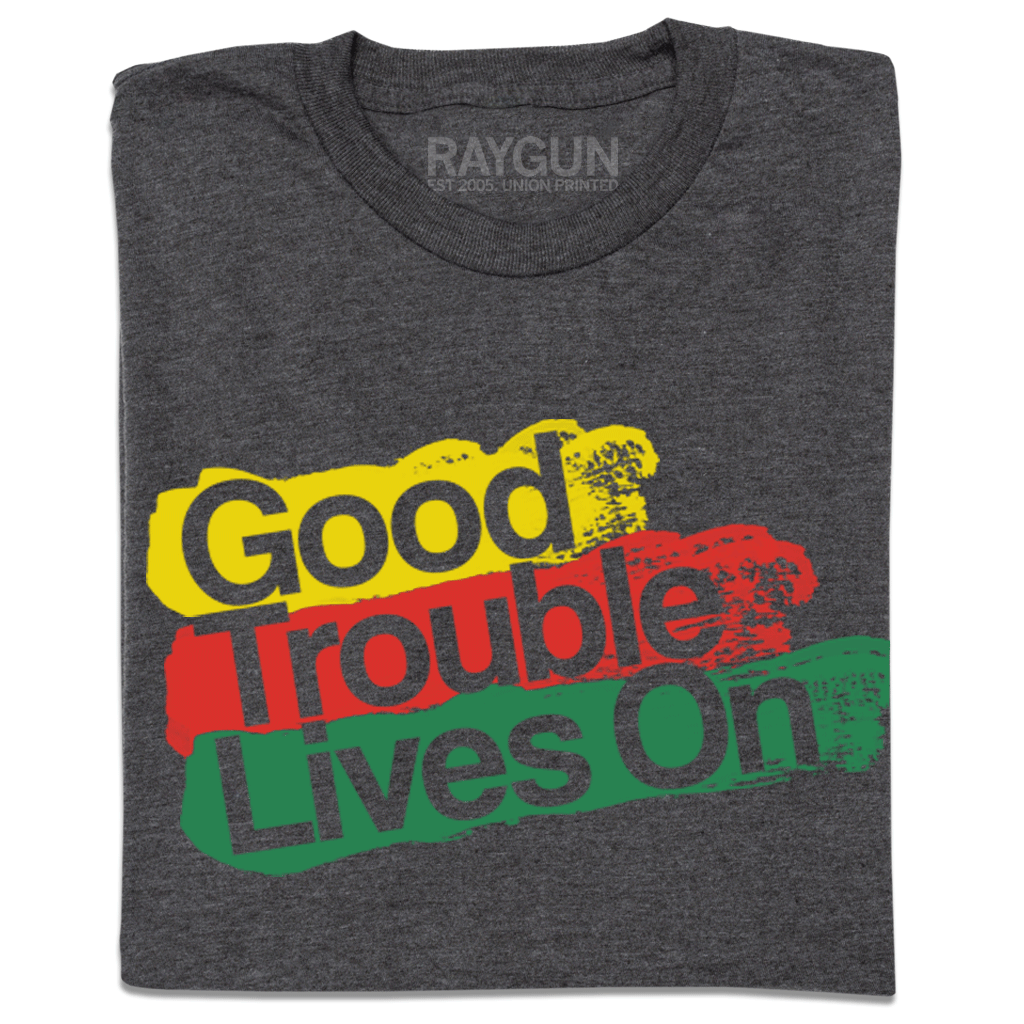 A dark gray Good Trouble T-shirt with the text Good Trouble Lives On printed in yellow, red, and green brushstroke-style blocks.