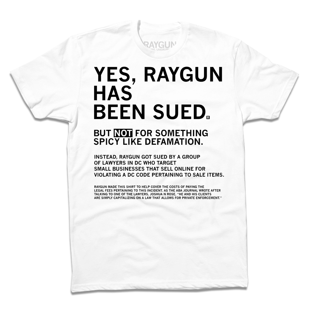 White sweatshop-free t-shirt with black text that reads: YES, RAYGUN HAS BEEN SUED. BUT NOT FOR SOMETHING SPICY LIKE DEFAMATION, followed by a paragraph explaining a legal dispute regarding DC code for small business online stores.