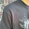 A person wearing a heavyweight black RAYGUN t-shirt with a white abstract graphic design.