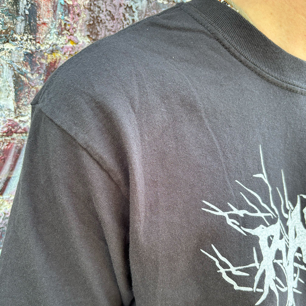 A person wearing a heavyweight black RAYGUN t-shirt with a white abstract graphic design.