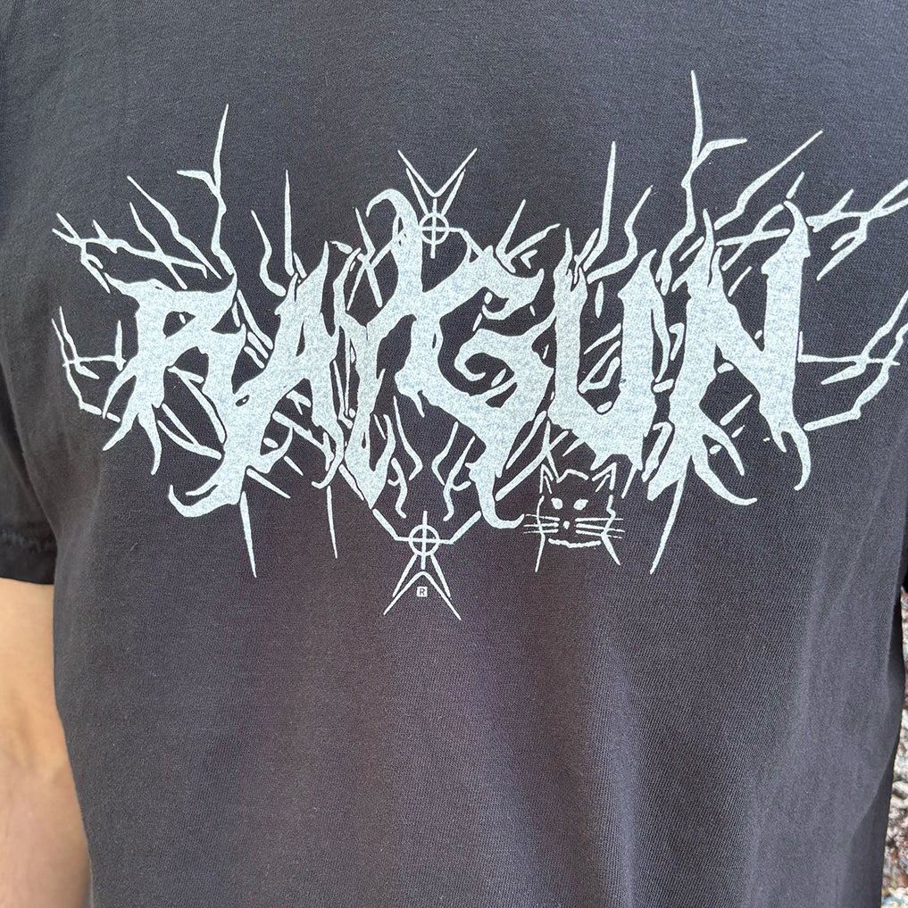 Heavyweight black RAYGUN t-shirt with the brand name in stylized, thorny white lettering above a small cat illustration.