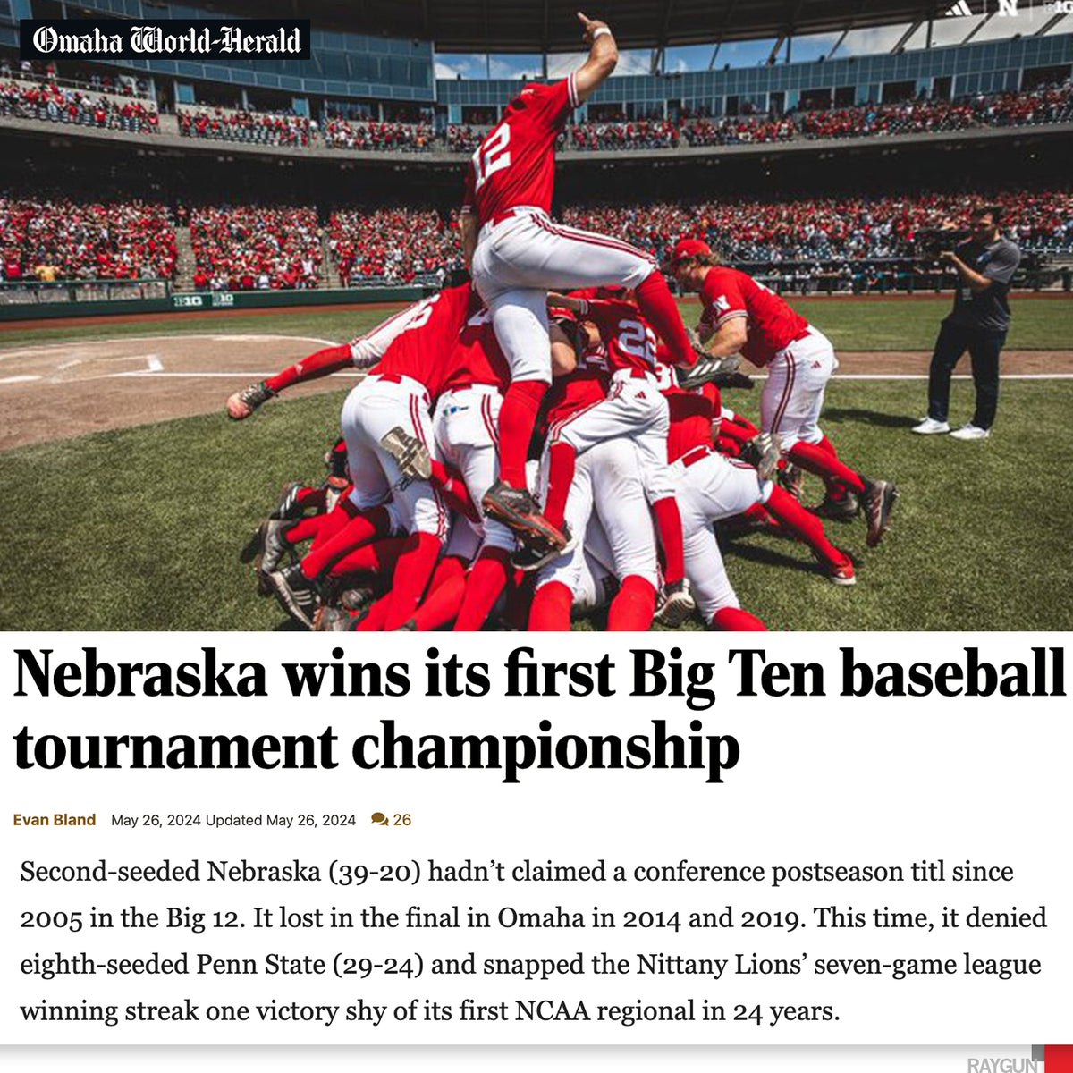 Nebraska baseball players celebrate in a pile on the field wearing Raygun t-shirts after winning the Big Ten tournament championship.