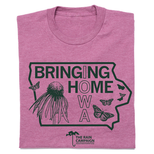 A folded, union-labor mauve t-shirt featuring a green graphic of Iowa with the text BRINGING HOME IOWA, a coneflower, and butterflies, finished with THE RAIN CAMPAIGN logo at the bottom.