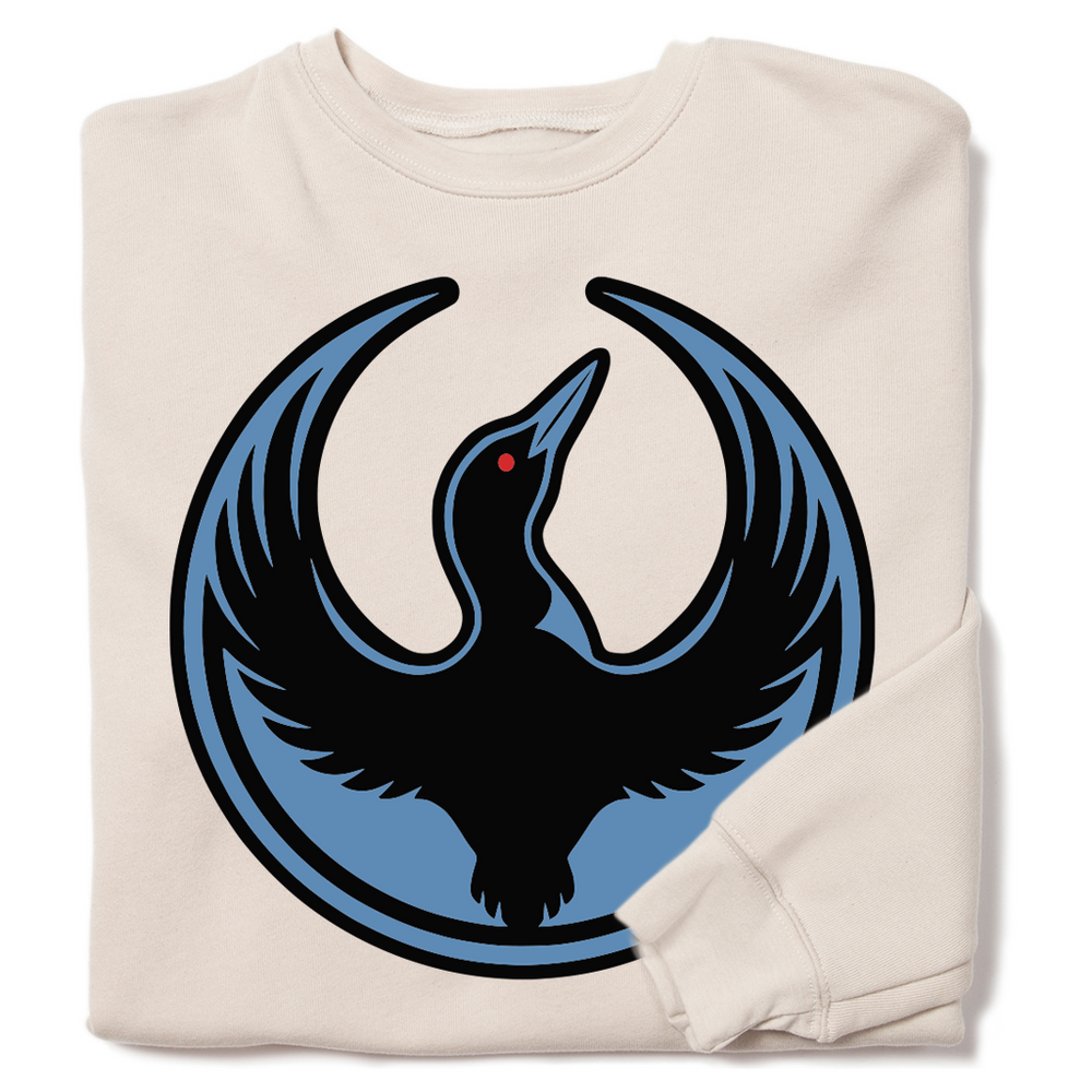 A folded cream crewneck sweatshirt with the Rebel Loon Alliance Logo. It uses a loon with outstretched wings to mimic the shape of the Star Wars Rebel Alliance Logo. The loon is printed blue & black with red eye.