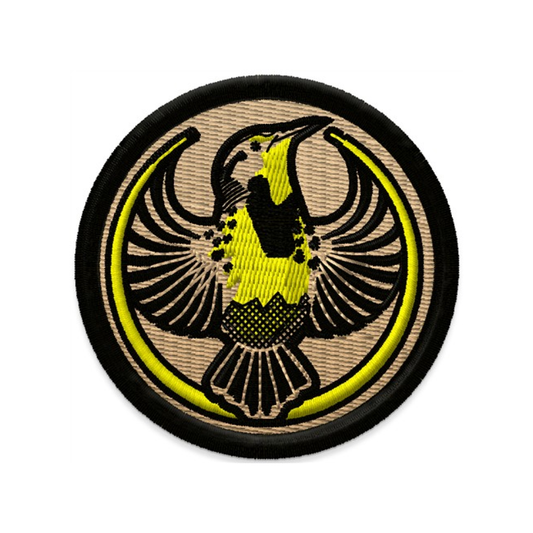 An embroidered circle patch with the Rebel Western Meadowlark Alliance Logo. It uses a western meadowlark with outstretched wings to mimic the shape of the Star Wars Rebel Alliance Logo. The western meadowlark is black and gold. The border of the patch is black and the rest of it is tan.