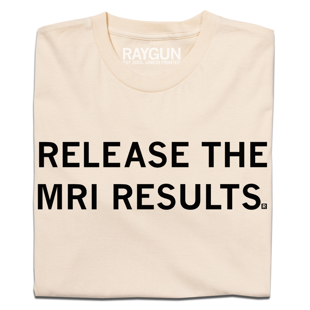 A folded cream t-shirt with blank ink text that reads "release the MRI results"