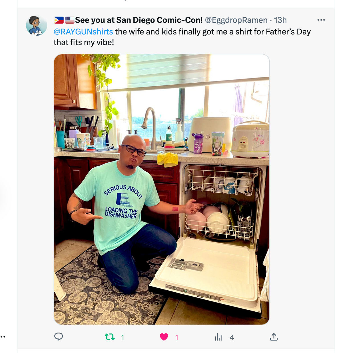 A man kneels in front of a loaded dishwasher wearing a union-made, light blue t-shirt that says, Serious about loading the dishwasher.